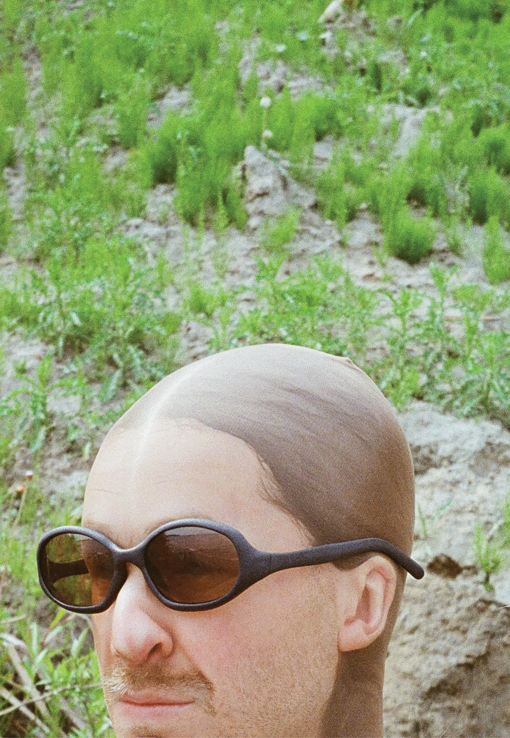 3D render of a bald model wearing black sunglasses with transparent grey lenses